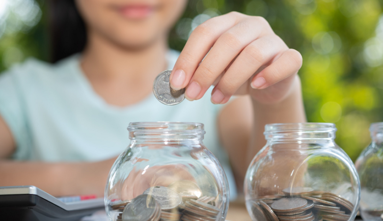 criança colocano moeda no cofre